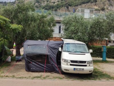 Camping Gardasee zu sehen ist ein weißer T4 Bus mit einem Vorzelt am Gardasee